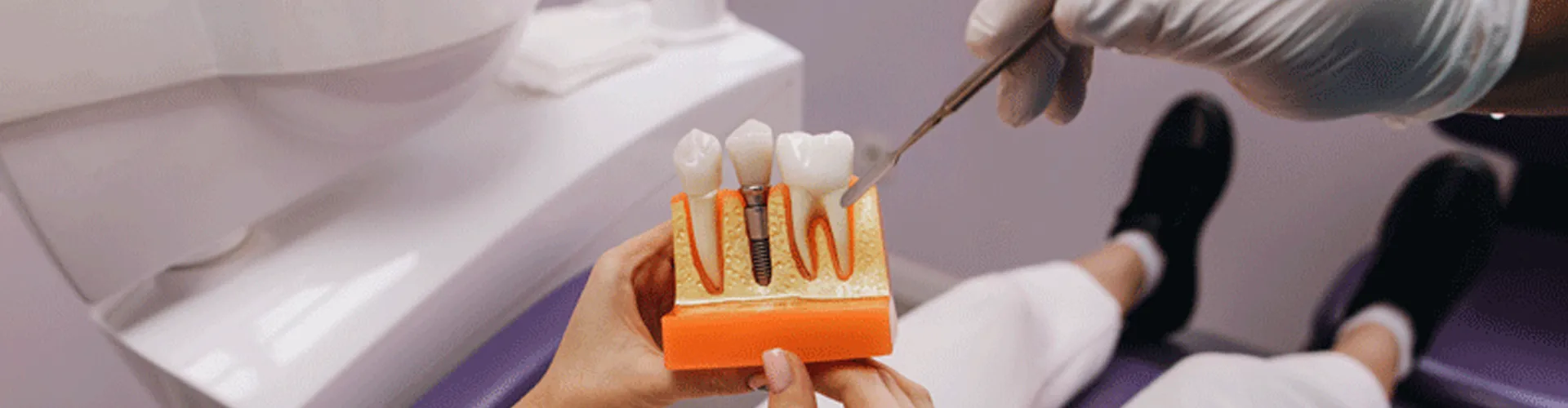 A dentist with a teeth model showing an implant.