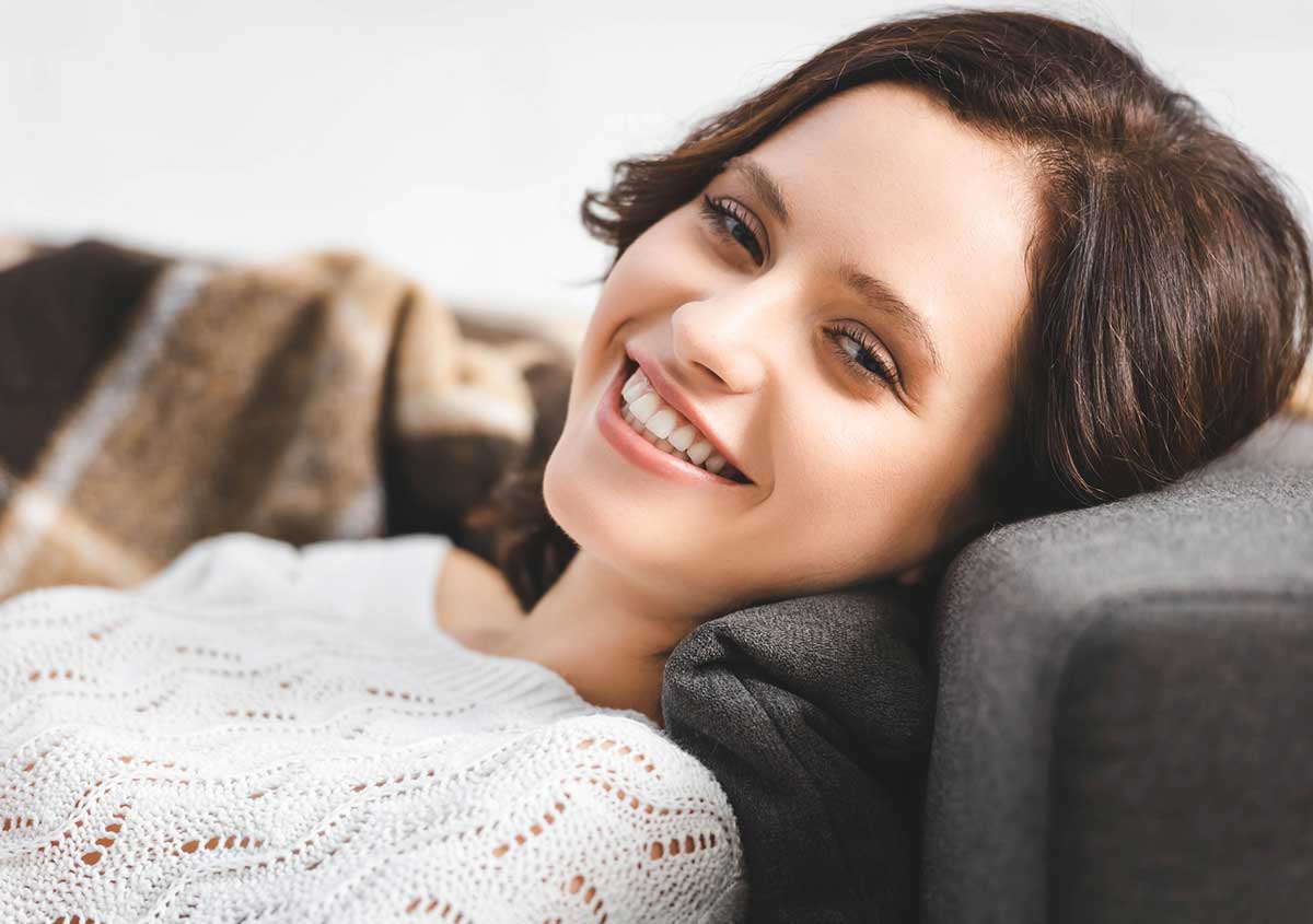 Woman smiling , leaning on sofa.
